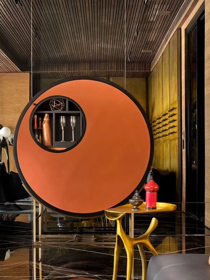 In this lounge, a bespoke circular bar storage unit hangs like a piece of art. The design echoes the circular motifs found throughout the home, creating thematic harmony and adding a unique, functional sculpture to the room.