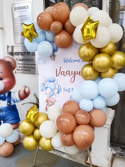 A welcome stand for baby Vaayu's first party. The custom board is framed with a beautiful balloon garland in pastel brown, blue, and gold.
