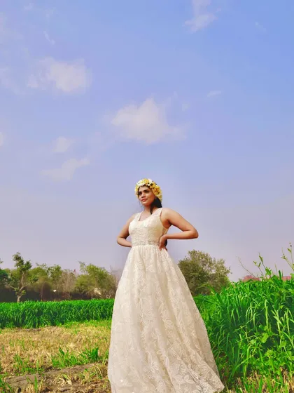 For this photoshoot in a field, I designed a bohemian-inspired A-line gown using a beautiful textured lace. The simple halter neckline and flowing skirt create an effortless, romantic vibe, which I styled with a yellow floral crown for a touch of color.