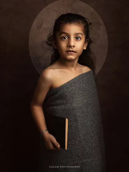 Wrapped in a simple grey cloth, this young girl's portrait is reminiscent of a classical painting. The halo of light behind her adds a touch of the divine.