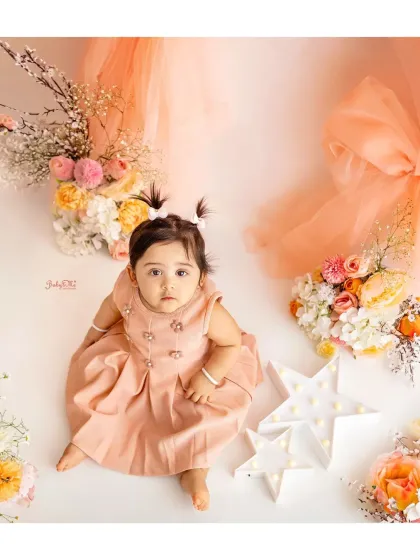 Looking up with the sweetest eyes. This high-angle shot shows off her pretty peach dress and the lovely floral arrangement in our studio.