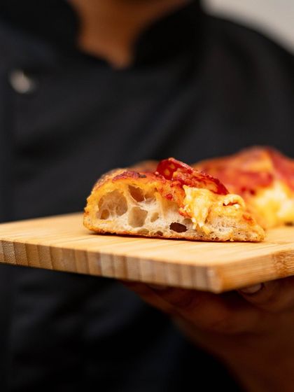 A close-up of the airy, open crumb of our Pizza Romana crust, a result of a long fermentation and high-hydration dough.