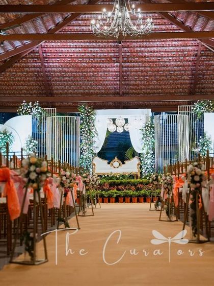 The view from the guest's perspective. The aisle is lined with beautifully decorated chairs, leading the eye towards the stunning reception stage.