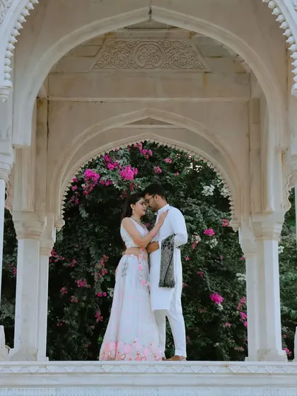 A romantic shot framed by a white marble archway, with vibrant bougainvillea adding a pop of color. It shows how I use natural elements to enhance the beauty of a pre-wedding photo.