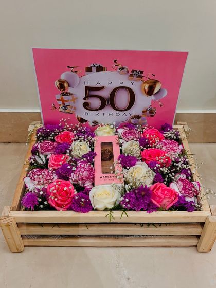 Another perspective of the 50th birthday floral crate, this time showing the full wooden crate and the lushness of the pink, white, and purple flower arrangement.