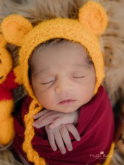 The perfect little bundle of joy. This newborn looks so content wrapped up as Winnie the Pooh, creating a timeless and adorable memory.