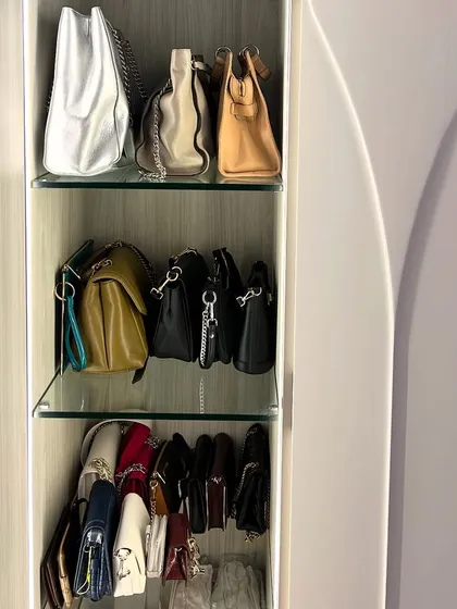 A curved wardrobe with custom glass shelves provides a unique and elegant home for this handbag collection.