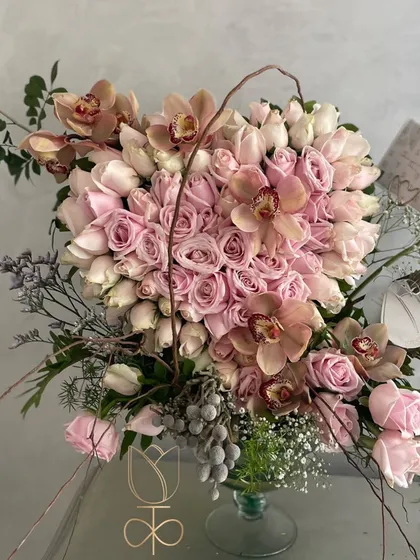 My take on the traditional gathering of roses. This beautiful heart-shaped display of soft pink roses is studded with the finest Cymbidium orchids, creating a demure, sweet, and gentle expression of love for Valentine's Day.