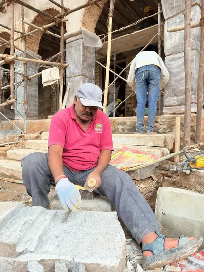 A stonemason shapes a block of granite for the steps of the RBANM's school. Using hand tools and traditional methods, he ensures the new stone will seamlessly integrate with the original 19th-century structure.