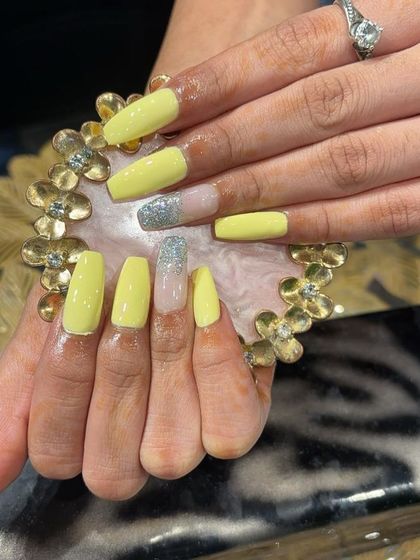 A bright and sunny yellow set with a silver glitter accent nail on long, square-shaped extensions.