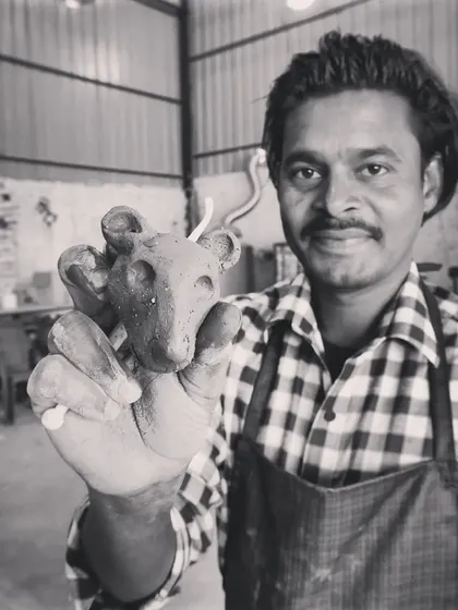 I'm holding up a small, whimsical mouse sculpture made by a student. Even the smallest creations are filled with personality.