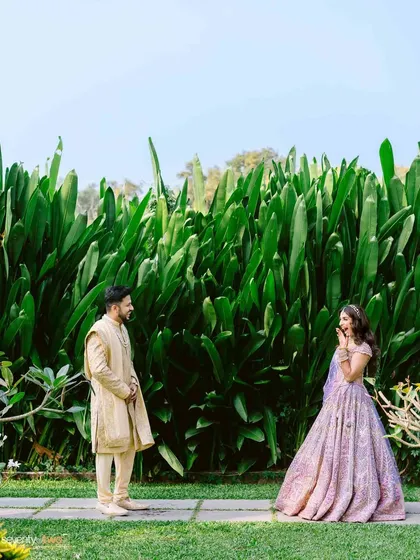 The couple's first look, a moment of surprise and delight set against a wall of vibrant green foliage at their Goa wedding.