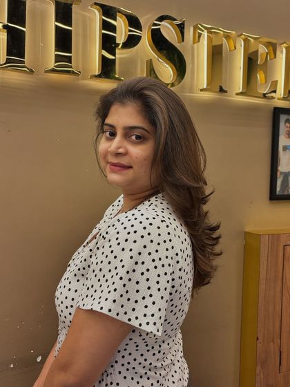 A side view of a layered haircut combined with a beautiful color blend. The style is designed to create movement and showcase the different tones in the hair.