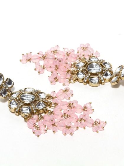 A cluster of craftwomanship. These brass earrings feature kundan stones and a beautiful cluster of pink flower-shaped beads. We can customize these in twelve different colors.