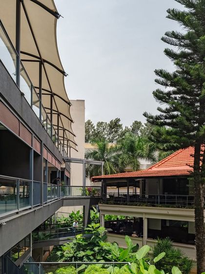 The interplay of canopies, bridges, and greenery between the new annexe and the existing buildings at the Koramangala Club. These transitional spaces are designed to encourage movement and informal social encounters.