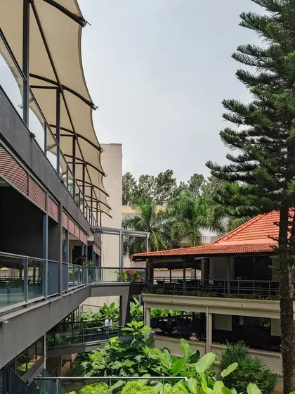 The interplay of canopies, bridges, and greenery between the new annexe and the existing buildings at the Koramangala Club. These transitional spaces are designed to encourage movement and informal social encounters.