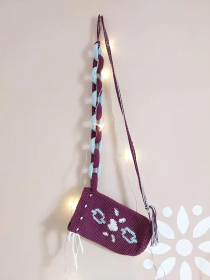 The Elara Bag hanging, showcasing its unique design with a tapestry crochet body and a chunky, two-toned chain strap.