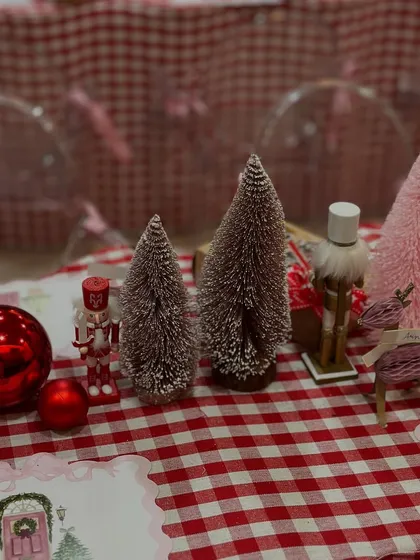 A close-up of the Christmas table setting, with nutcrackers, bottle brush trees, and shiny red ornaments creating a festive centerpiece.