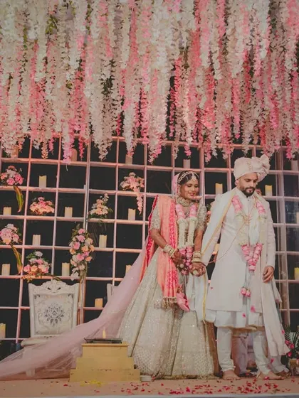 A full view of the stunning wedding stage at Radisson Karjat, with a ceiling of hanging flowers and a wall of candles creating a romantic and dreamy ambiance for the couple.