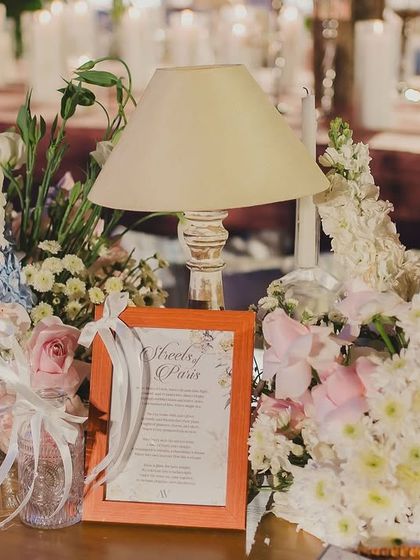 A charming decor vignette with a table lamp, florals, and a framed menu, adding to the romantic, story-filled atmosphere of the Parisian night.