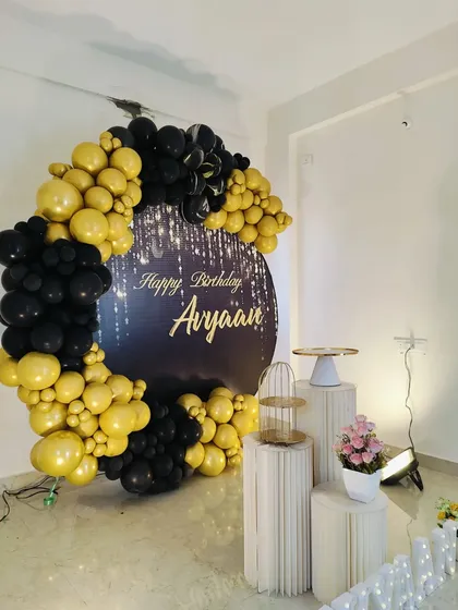 An angled view of the black and gold setup, showing the arrangement of the props and balloon arch.
