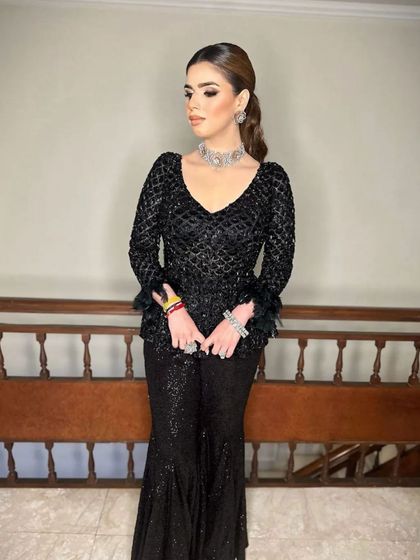 A full-length view of the client, where her sleek ponytail adds a touch of modern sophistication to her embellished black ensemble.