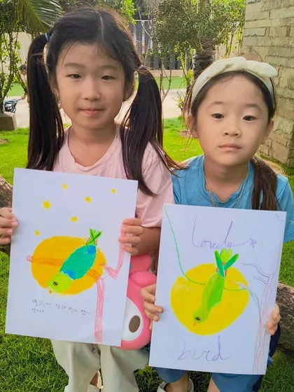Two students from our parrot class holding up their colorful creations, each with its own unique charm.