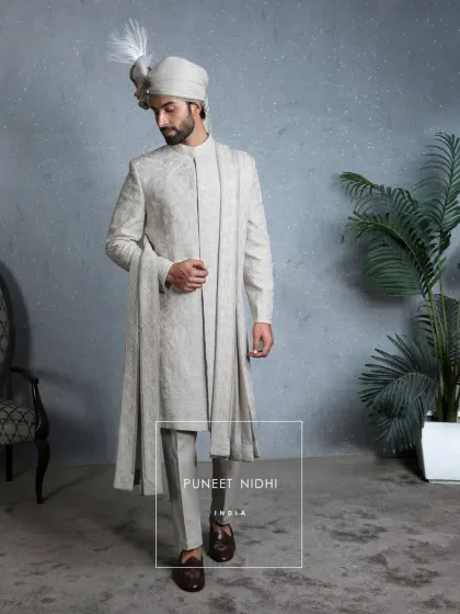 Intricacy meets majesty in this ivory jacquard sherwani. The fabric is textured with floral and vine artistry, brought to life with hand-finished detailing, creating a masterpiece of tradition.