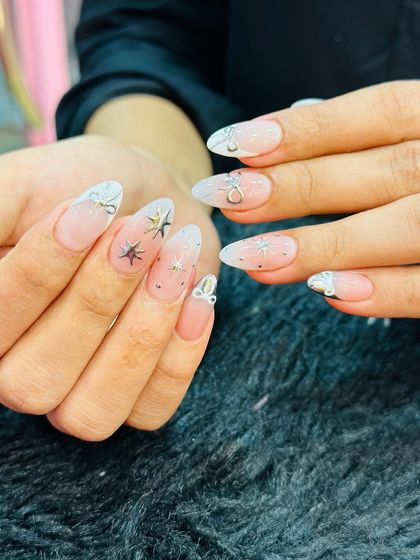 A celestial design with plenty of sparkle. This look features a soft white ombre tip with delicate silver star and bow-shaped gems, creating a dreamy and magical feel.