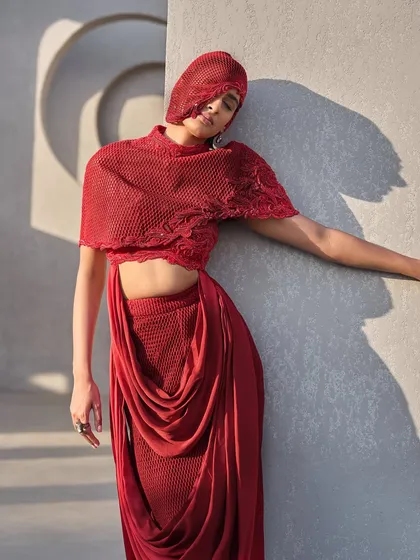 A statement silhouette in red that blends structure with fluidity, featuring a dual-panel mesh top and a double cowl drape skirt.
