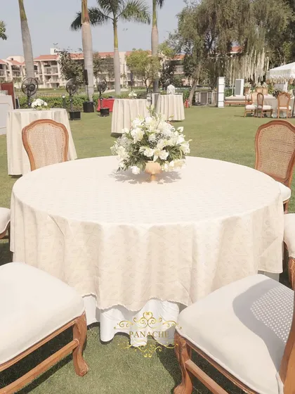 A wide view of the guest seating on the lush green lawn, creating a beautiful contrast with the white and gold decor.