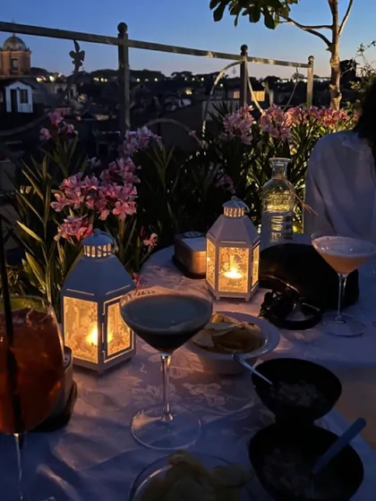 An evening of cocktails and conversation on a rooftop. This setup for a private dinner includes expertly crafted martinis and appetizers, with candle-lit lanterns creating a serene and romantic mood against the city skyline.