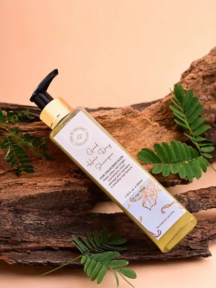A naturally styled shot of a shampoo bottle for Pure by Priyanka, resting on a piece of wood. This composition reinforces the brand's connection to natural and botanical ingredients.