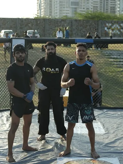 Ready for battle. Two of our fighters standing with the coach inside the octagon, focused and prepared for the challenge ahead.