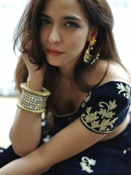 A close-up portrait focusing on the details of traditional Indian fashion. The shot highlights her elegant earrings and bangles, along with the rich texture of her embroidered velvet top, creating a vibrant and culturally rich fashion image.