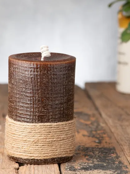 This large, brown pillar candle has a beautiful texture and is wrapped with jute rope for a rustic, earthy feel. It's a great piece for a cozy corner.