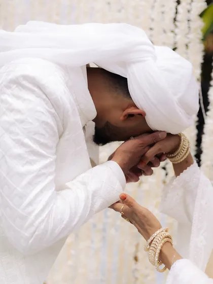 A tender moment where the groom kisses the bride's hand. This gesture of respect and love, captured up close, is a beautiful highlight of their Nikaah ceremony.