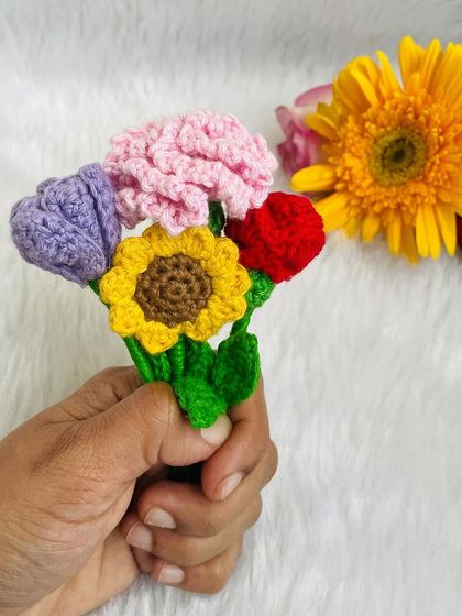 A tiny, handheld bouquet of mini crochet flowers, including a carnation, sunflower, and rose. It’s a small burst of color and joy.