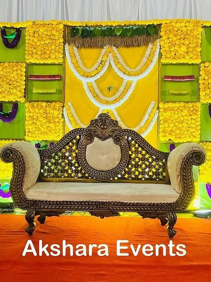 A classic yellow and green themed backdrop for a Seemantham ceremony. The design uses panels of marigolds and is decorated with garlands of white flowers in a traditional pattern.