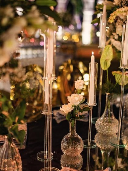 A close-up of the mirrored tablescape from the wire mesh wedding, with delicate crystal candelabras and single stems in bud vases.