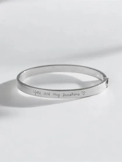 A clean product shot of a silver cuff bracelet engraved with the handwritten-style quote "You are my sunshine ♡". This is a perfect example of how I can engrave personal messages and affirmations.