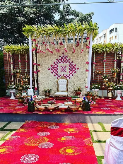 We also specialize in beautiful outdoor setups for traditional functions. This Seemantham (baby shower) ceremony features a floral wall of white and pink against a rustic brick background, complete with a traditional white chair for the mother-to-be.