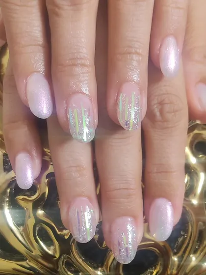 This set combines a soft, shimmery pink polish with accent nails that have vertical holographic foil strips for a modern, striped look.