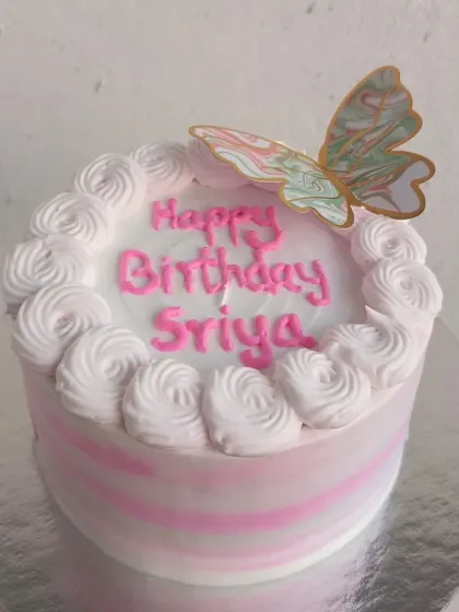 A minimalist pink cake with a single butterfly topper, perfect for a simple yet sweet celebration.