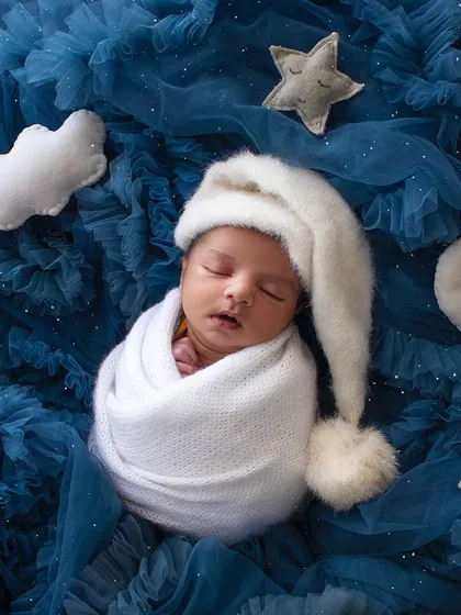 A peaceful newborn dreaming amongst the stars. My celestial-themed sessions use soft fabrics and props to create a magical, sleepy setting for your little one's first portraits.