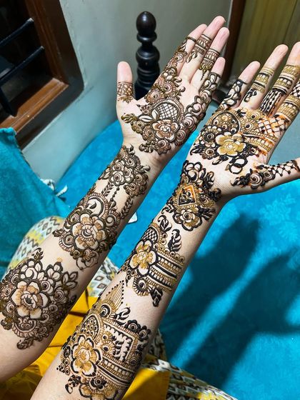 This design features a beautiful mix of styles, with one arm showcasing bold floral work and the other a more geometric, architectural pattern. It's a perfect example of custom bridal henna.