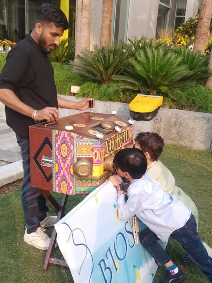 Children gather around the bioscope, fascinated by the traditional movie-viewing machine. It's a wonderful, low-tech activity for weddings and cultural events.