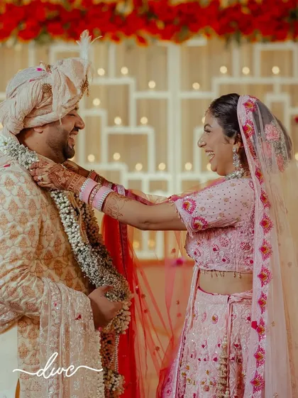 The joy and laughter during a Jaimala ceremony are perfectly captured in this candid shot, as the bride playfully places the garland on her groom.