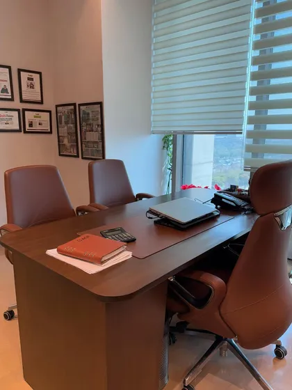 A view of the executive desk setup, showing the clean lines and rich wood finish. The design prioritizes functionality with a large work surface and accessible storage, while maintaining a polished and professional look.
