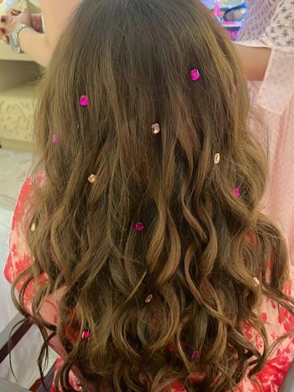 Jewel stones are a unique way to accessorize hair. Here, we used pink and clear gems scattered through soft waves to add a touch of sparkle and color that complements the client's outfit.